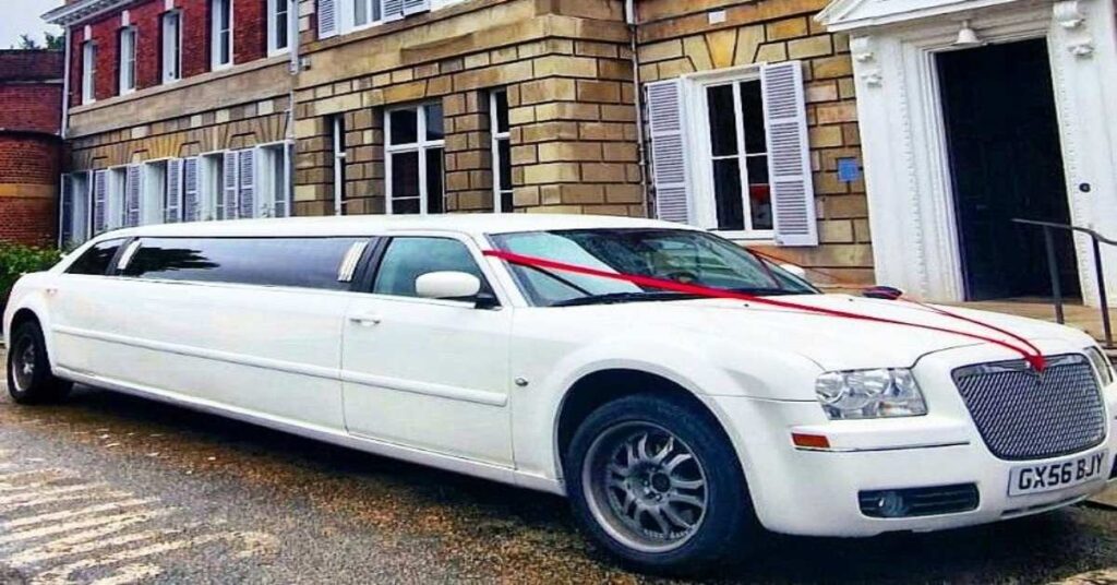 White Chrysler limo with big red ribbon front tied